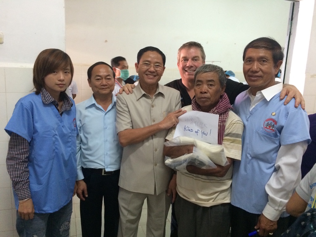 Steve Bender and the Cambodia team with a smiling hand recipient holding his note reading Kind of you