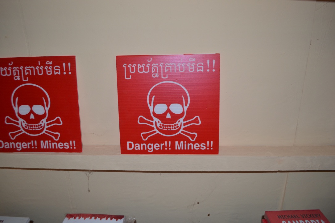 Red Danger Mines warning signs with a skull and crossbones in Khmer and English